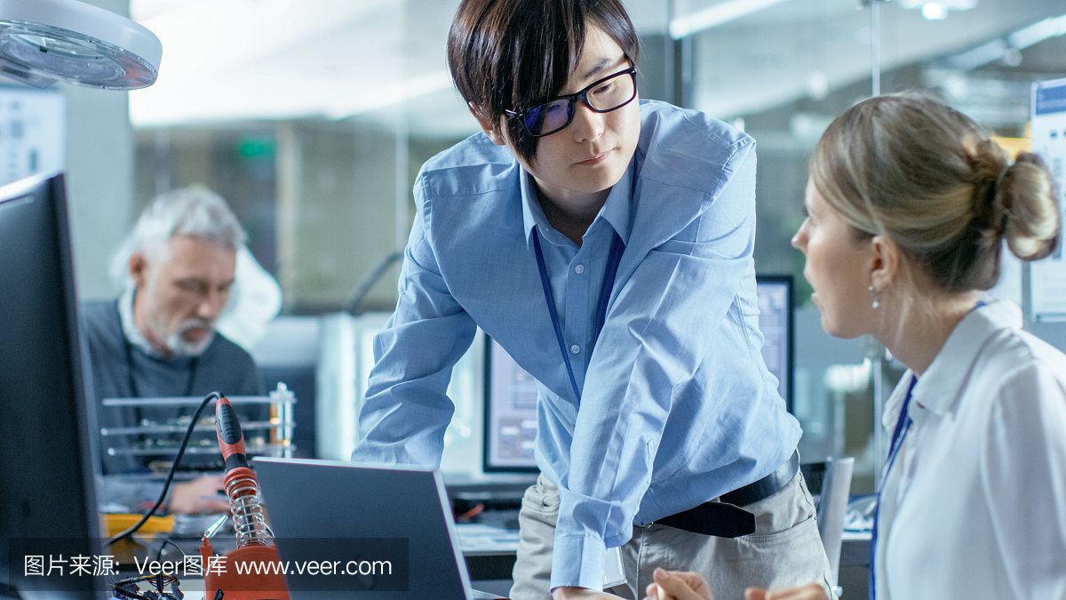 女計算機科學(xué)家用綠色屏幕模型連接電路板到她的筆記本電腦。她在先進(jìn)技術(shù)實驗室工作。